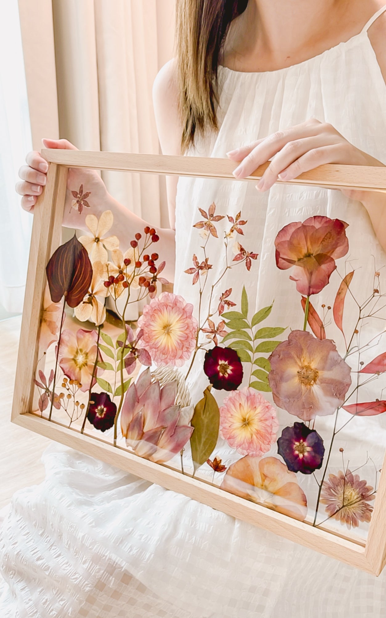 A person holder a bridal/wedding pressed flower in wooden frame